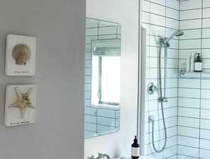 Bathroom features a glass shower enclosure, handheld showerhead, and a window with a view.