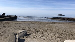 A beach with a rocky outcrop and a distant island. - 2 Bed Villa Sleeps 4 - Wifi, Garden, Sea Views (Looe)