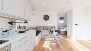 Un espacio habitable moderno y bien iluminado, con cocina, mesa de comedor y sofá.