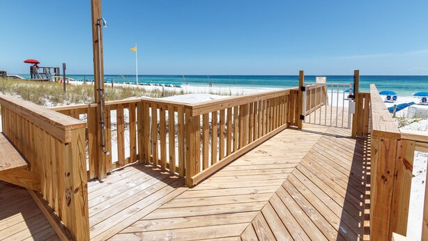 A wooden boardwalk leading to a beach with a lifeguard tower and umbrellas. -  🦩Book Me Baby! Gulf View ~ It's The Treasure You Have Been looking For!🦩 (Fort Walton Beach)