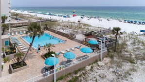 A pool area with lounge chairs and umbrellas, a beach with umbrellas and people, and a clear view of the ocean. - 🦩Book Me Baby! Gulf View ~ It's The Treasure You Have Been looking For!🦩 (Fort Walton Beach)