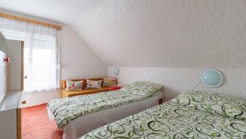 Ein Schlafzimmer mit zwei Betten, einer Holzbank, einem kleinen Tisch und einer Wandleuchte.