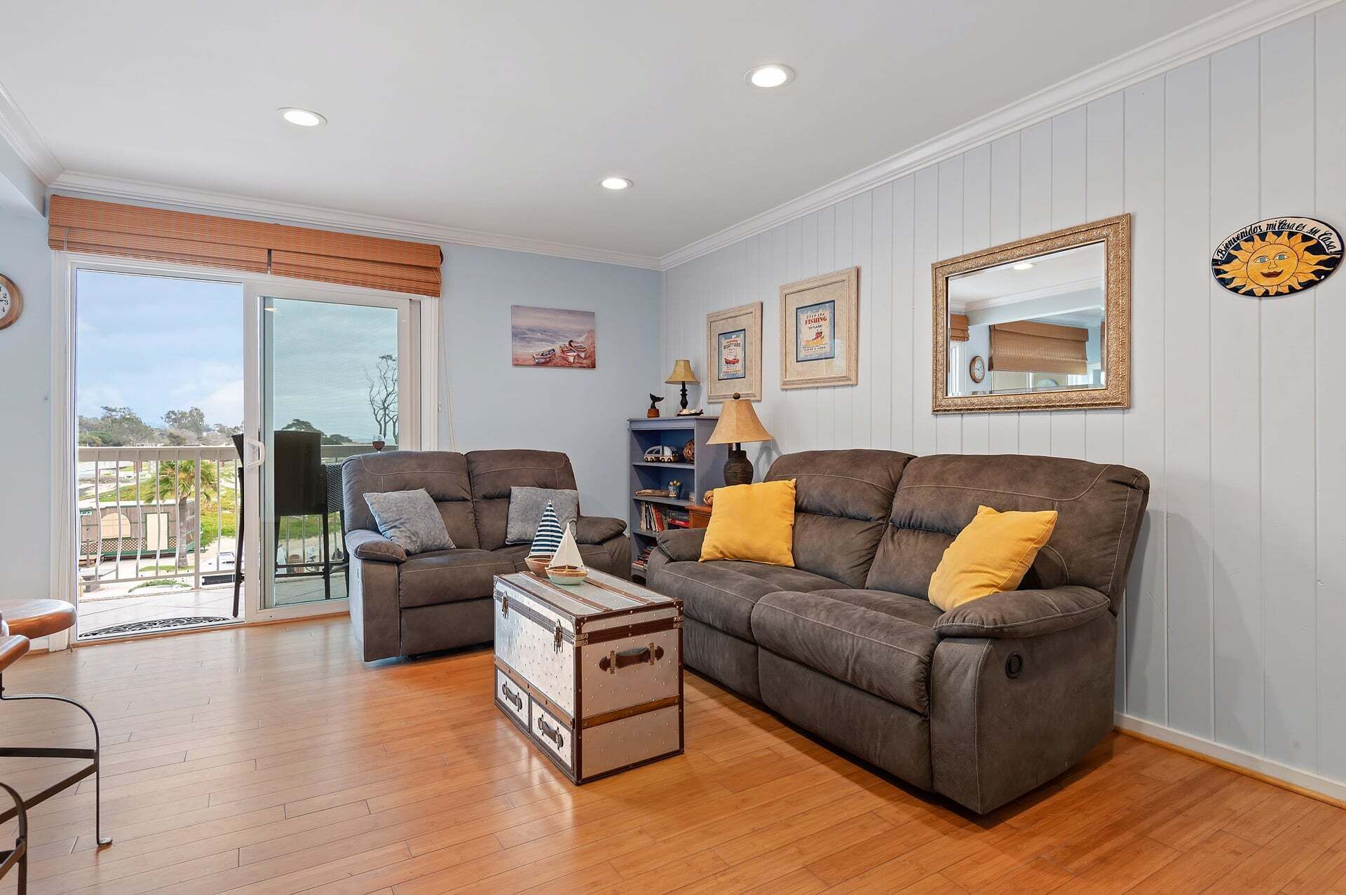 A living room with two sofas, a small table, a bookshelf, and a large window.