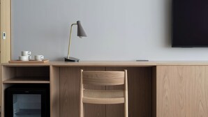 Een moderne werkruimte met een houten bureau, een stoel, een lamp, een televisie en een minibar.