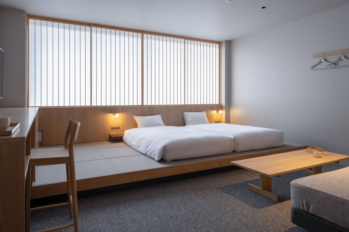 Een moderne hotelkamer met een bed, een bureau, een stoel en een klein tafeltje.