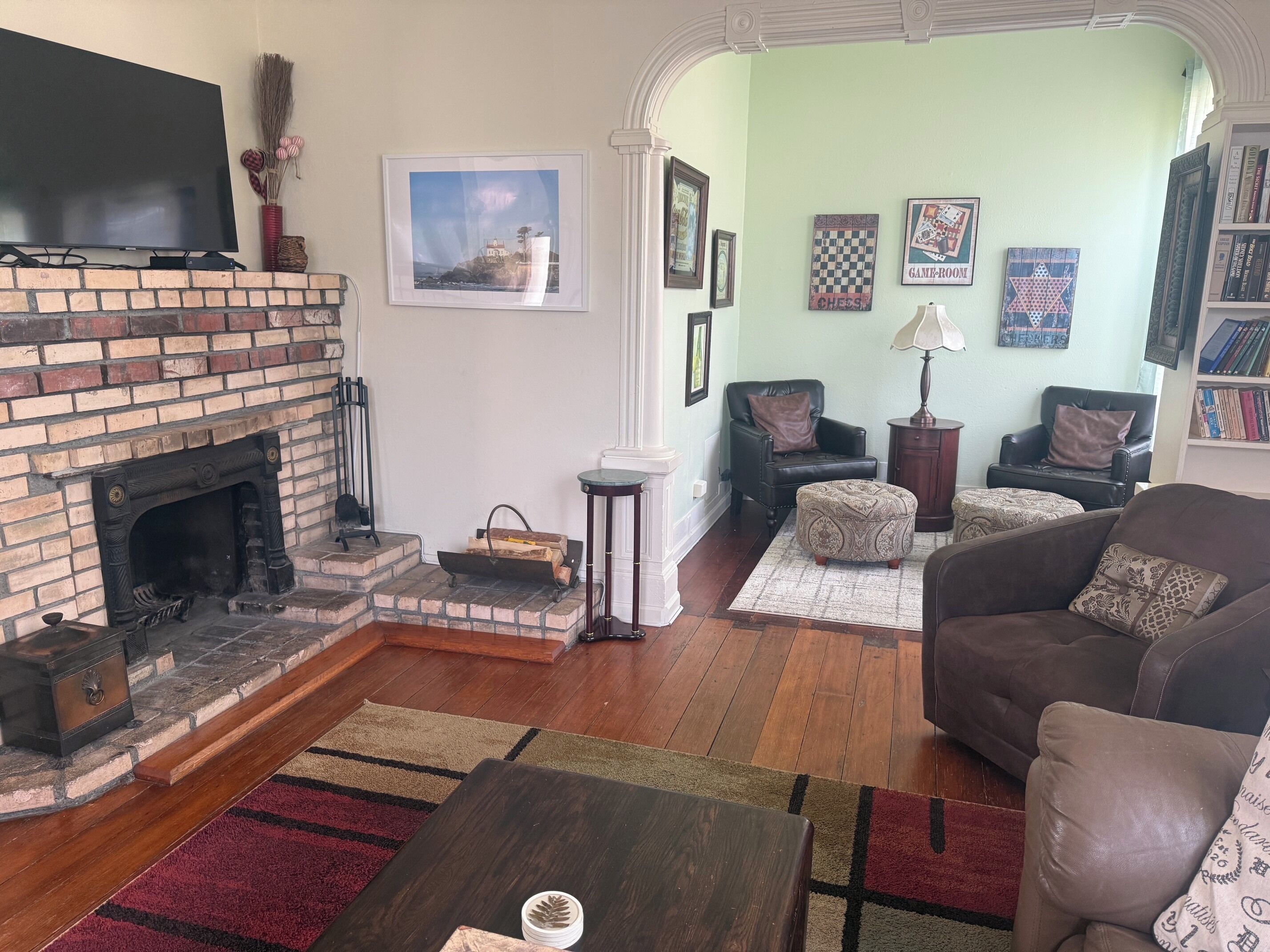 A living room with a fireplace, leather sofas, a coffee table, and a bookshelf.