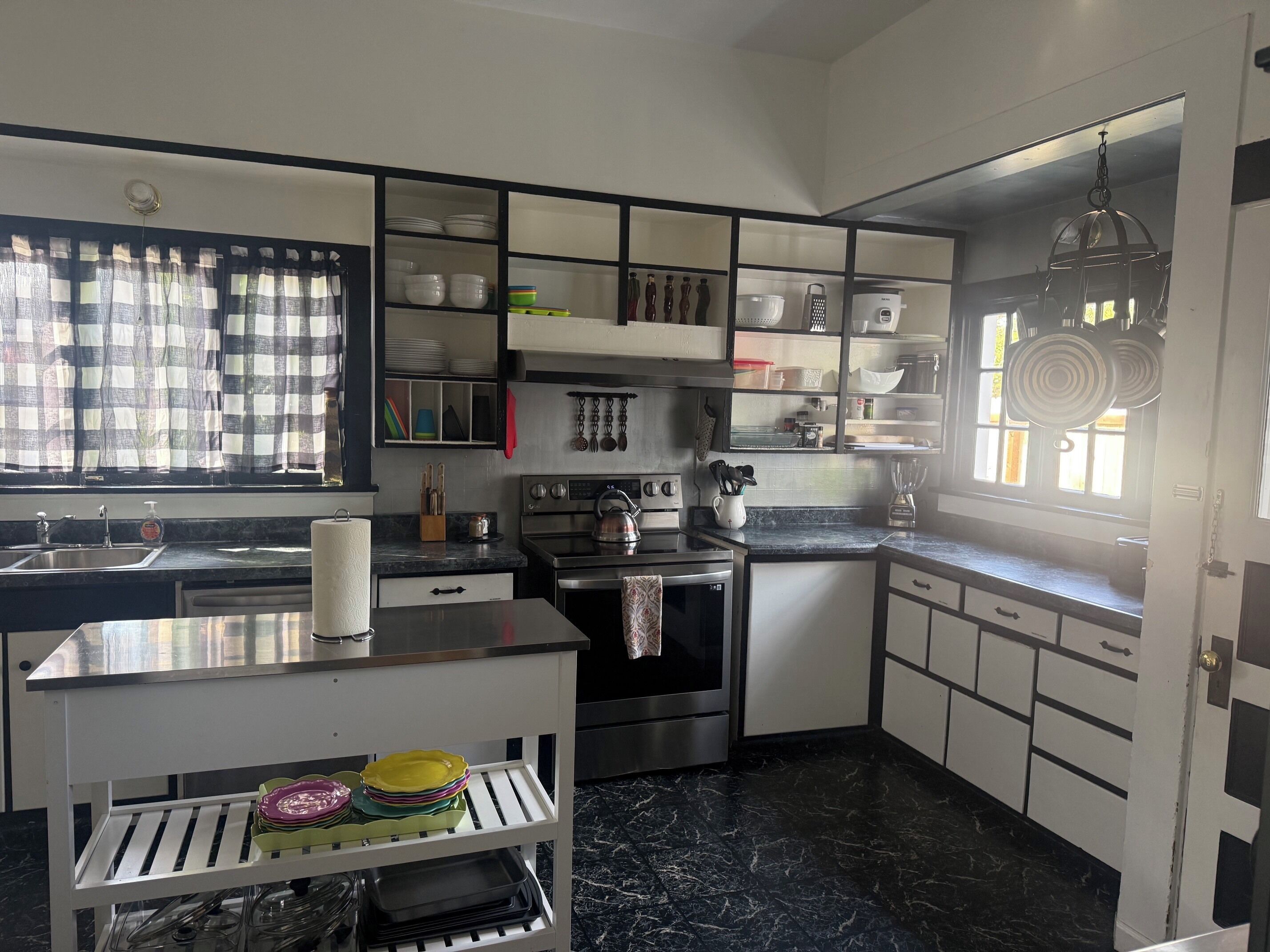 Una cocina moderna con horno integrado, un lavamanos y una ventana con cortinas.