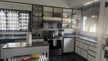 Una cocina moderna con horno integrado, un lavamanos y una ventana con cortinas.