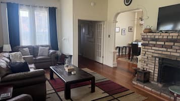 A living room with a sofa, coffee table, fireplace, and a television.