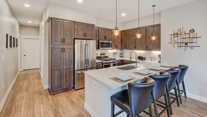 Una cocina moderna con armarios de madera, electrodomésticos de acero inoxidable y una isla central con taburetes de bar.