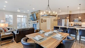 Una cocina moderna con una isla central, mesa de comedor de madera y sillas negras.