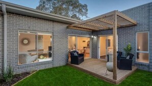 Ein modernes Haus mit überdachter Terrasse, Ziegelaußenwand und gepflegtem Rasen.