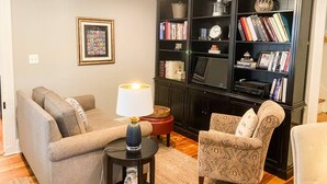 Ein Wohnzimmer mit einer Couch, einem Sessel und einem Bücherregal voller Bücher und Dekoration.