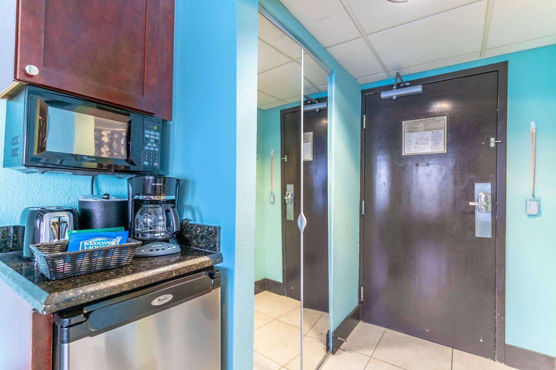 Una kitchenette con microondas, cafetera, tostadora y una cesta de café Maxwell House.