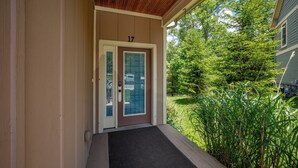 Ein Haus mit der Hausnummer 17, einem überdachten Balkon und einem Vorgarten mit hohem Gras.