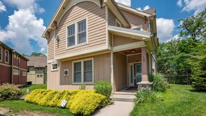 Ein zweistöckiges Haus mit Veranda, Garage und gepflegtem Rasen.