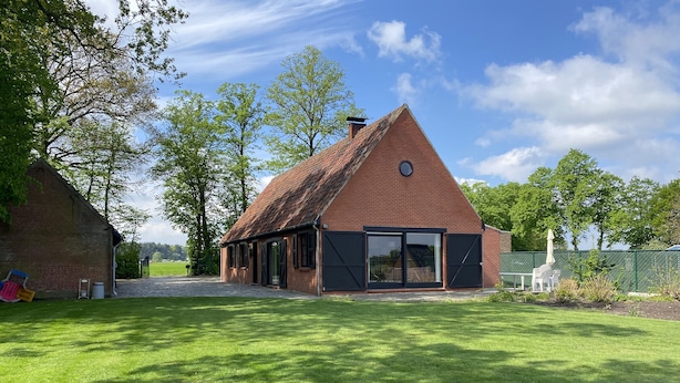 A brick house with a sloped roof and large glass doors, surrounded by a well-maintained lawn and trees. - Holiday home surrounded by woods and meadows (Grote Brogel)