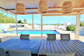 A covered outdoor area with a pool, lounge chairs, and wicker lamps. - Aaron - holiday home with stunning views and private pool in Calpe (Calpe)