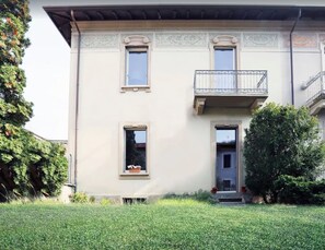 A two-story building with a balcony, a door, and a window.