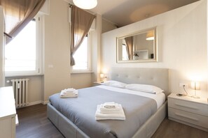 Habitación de hotel con cama, mesitas de noche, un espejo y una ventana con cortinas.