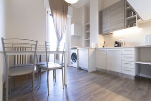 Una cocina moderna con lavadora, comedor con sillas y muebles empotrados.