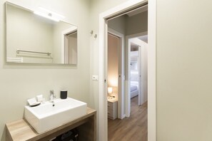 Un baño con lavamanos blanco, espejo y perchero.