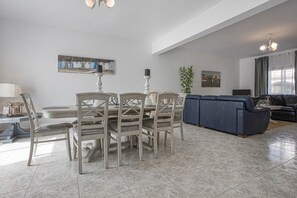 A dining area with a round table and chairs, a sofa, and a television in a living room.