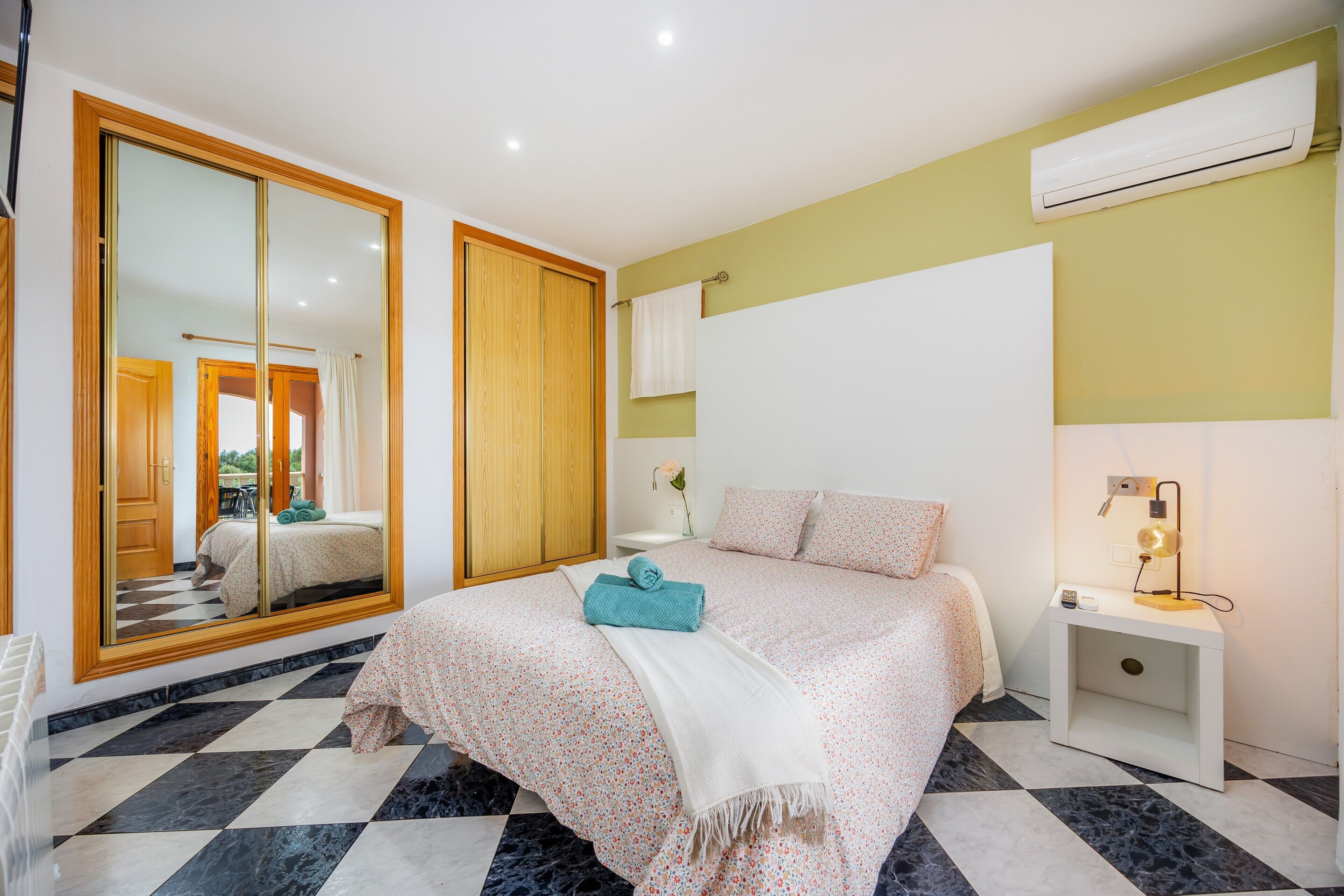 Un dormitorio con cama, mesita de noche, espejo y armario.
