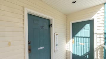 A teal door with a welcome sign, a mailbox, and a number sign '18C'.
