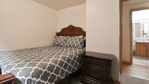 Ein Schlafzimmer mit einem Bett, einem Nachttisch, einer Kommode und einer Tür zu einem Badezimmer.