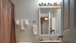 Ein Badezimmer mit Toilette, Waschbecken, Spiegel und Duschvorhang.