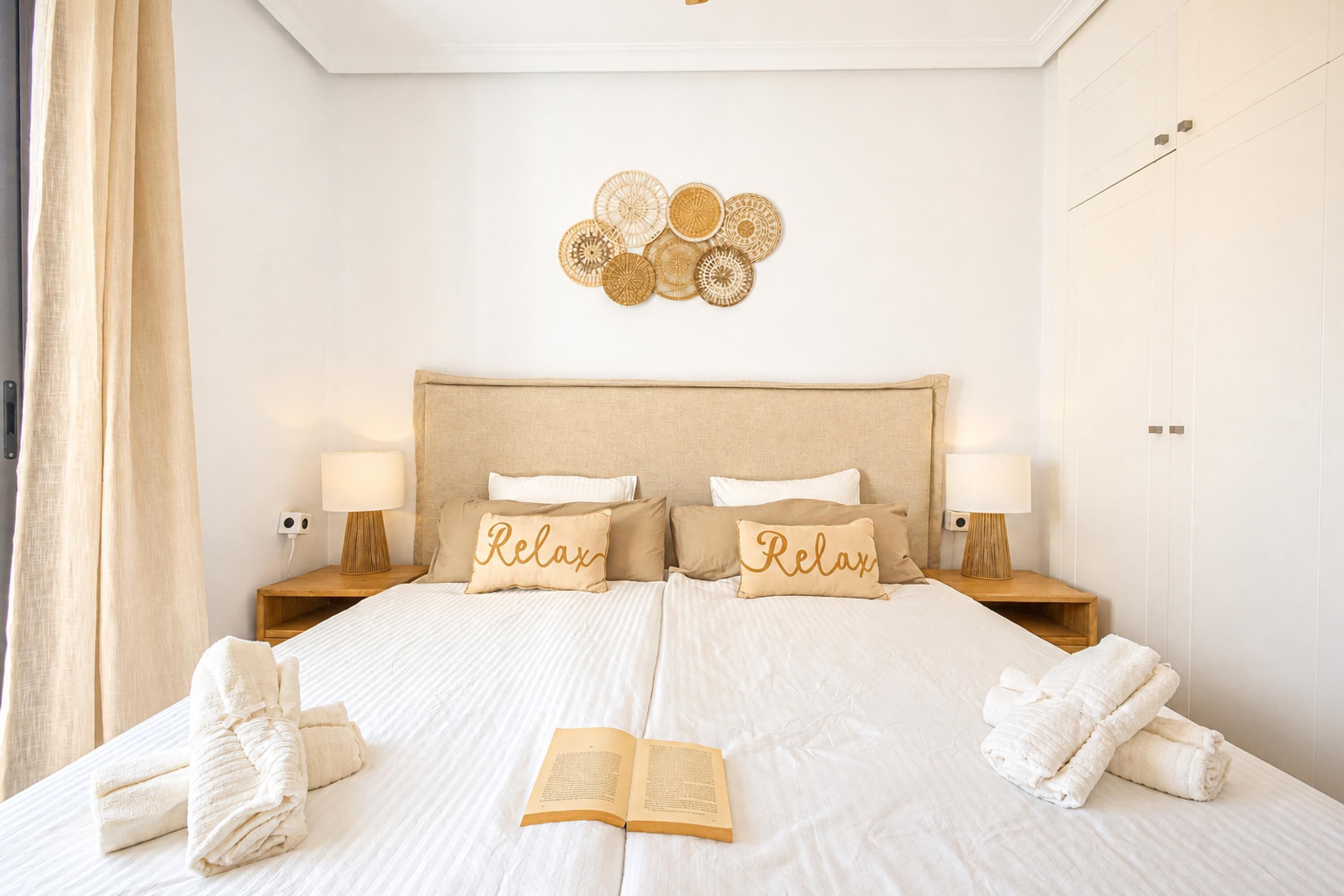 Un lit bien fait, avec deux oreillers, une lampe de chevet et un livre posé sur le lit.