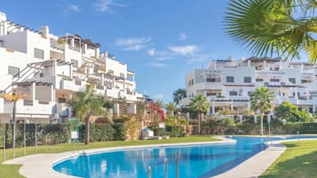 Una piscina de vora corba, envoltada d'un pràt ben cuidat i palmeres.