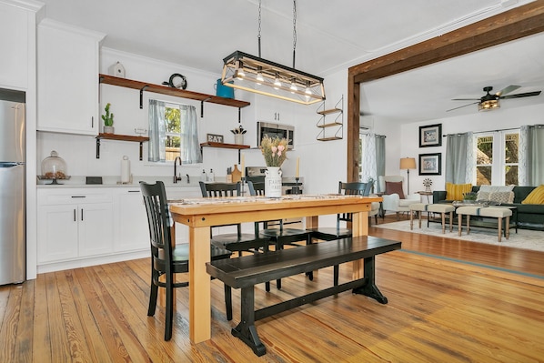 A spacious kitchen with a wooden dining table, black chairs, and a hanging light fixture.