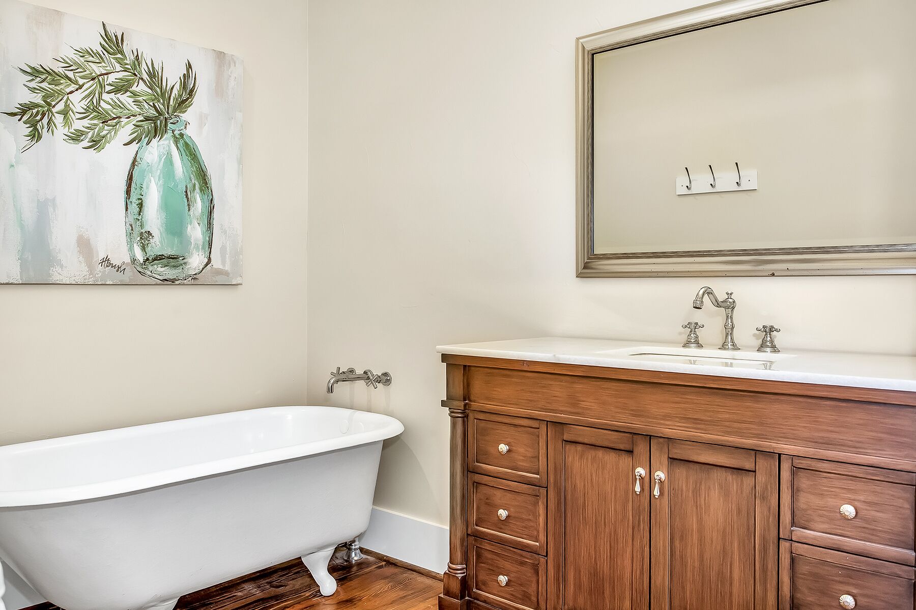A bathroom with a clawfoot tub, wooden vanity, and a mirror above the sink.