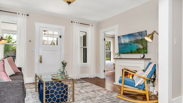 A living room with a sofa, a coffee table, a rug, a painting, and a fireplace.