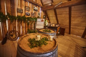 Un interior rústico de madera con mesas de forma cilíndrica, techo de madera y cuadros en las paredes.