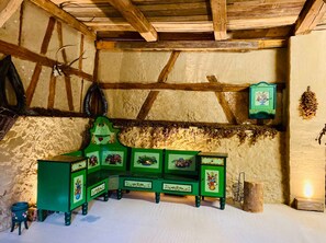 A rustic room with exposed wooden beams, a green wooden cabinet with floral designs, and a small stool. - Ferienwohnung Dorfblick - Ferienhof Stephanus (Ebermannstadt)