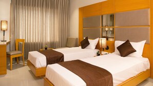 A hotel room with two beds, a desk, a chair, and a large mirror.