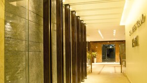 A hallway with a marble floor, a potted plant, and a reception desk.