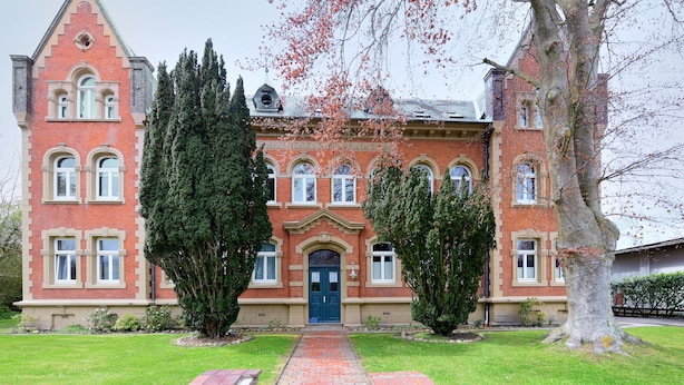 En stor, historisk bygning med en symmetrisk facade, mange vinduer og en midterindgang.