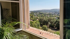 En balkon med udsigt over byen og grønne omgivelser.