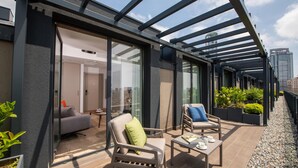 A modern outdoor balcony with seating and a small table, surrounded by potted plants and a city view. -  Antwell Suites (Istanbul)