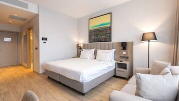 Habitación de hotel moderna con una cama grande, una mesita de noche, una lámpara y un cuadro en la pared.