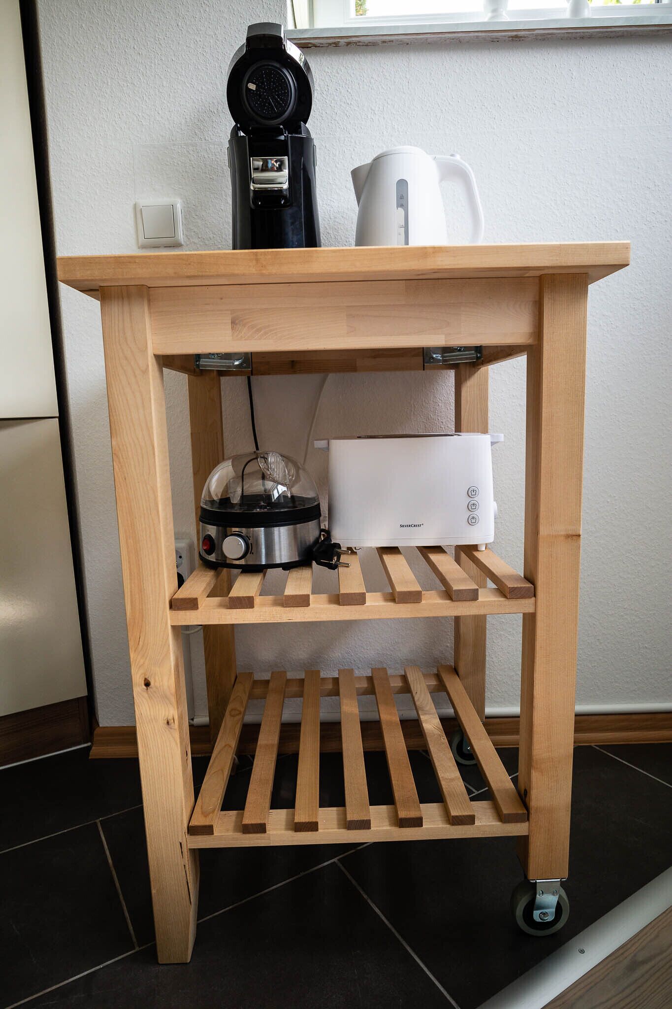 A wooden kitchen cart with a kettle, a coffee maker, and a toaster.