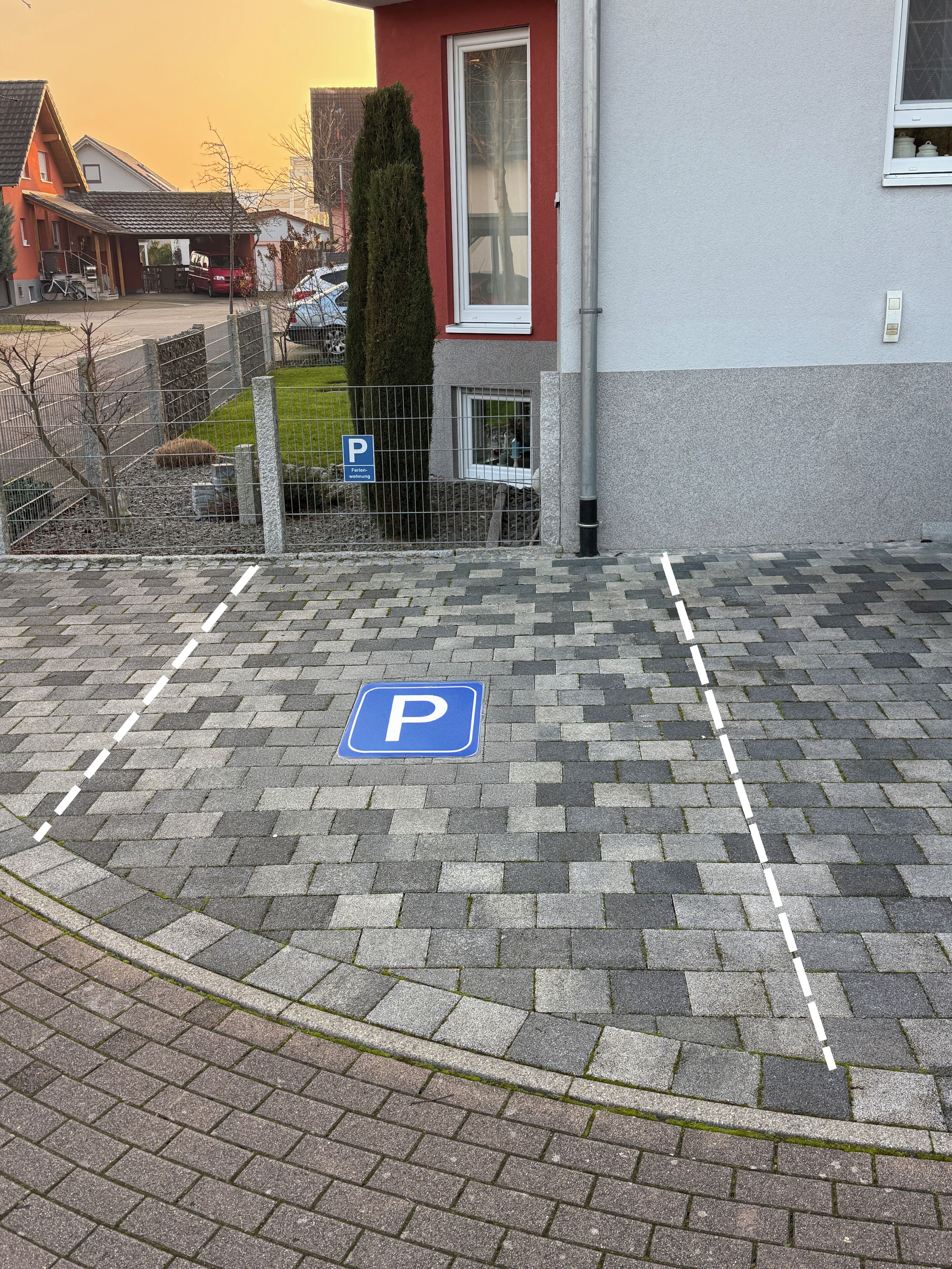 Een parkeerplaats met een blauw 'P'-bord, verhard met grijze bakstenen, en een witte lijn die de parkeerplaats afbakent.