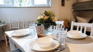 A dining table set with white plates, bowls, cutlery, and a vase of flowers. A sign with customer reviews is visible.