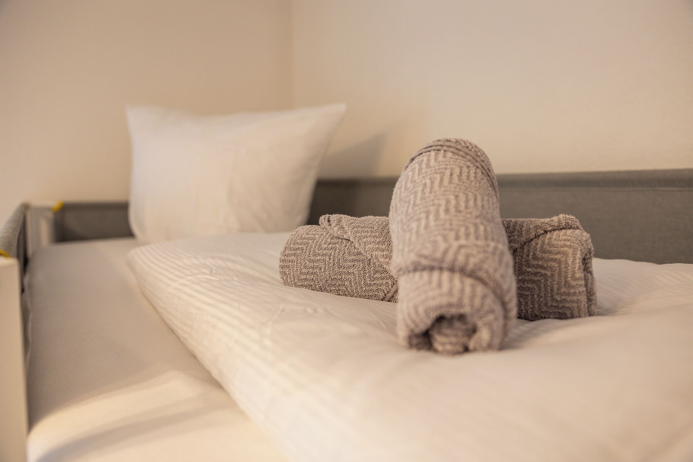 A neatly made bed with a folded blanket and pillows.
