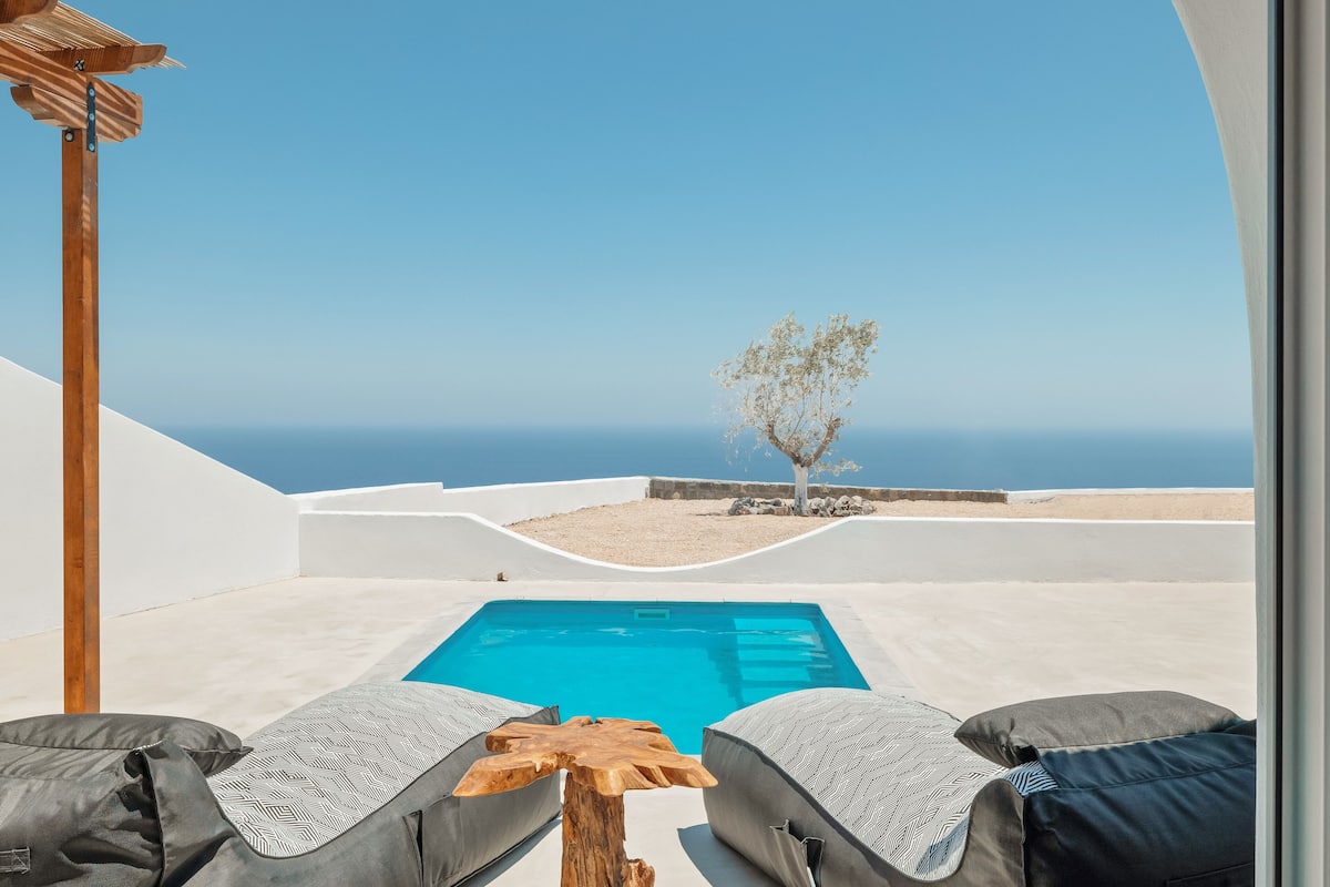 A poolside area with lounge chairs and a view of the sea.