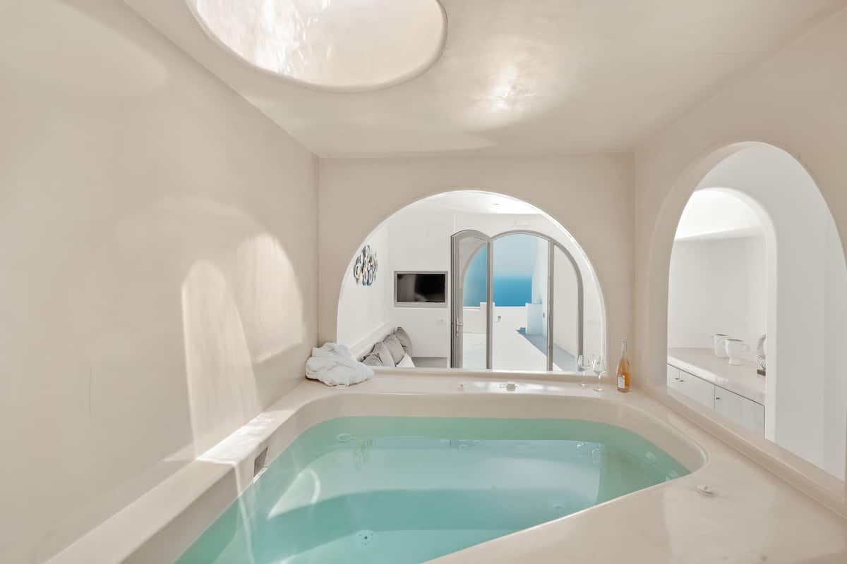 A modern bathroom with a large bathtub, a shower area, and a view of the sea.